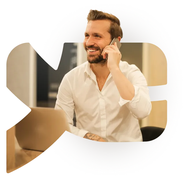 A YESbusiness user on the phone at their laptop, in a photo cropped to the shape of the YESbusiness logo.